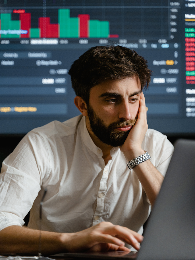 a man sit front of the laptop and backgroud showing stock maket chart